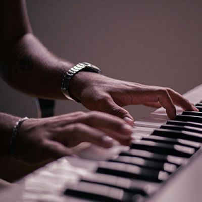 the hands of a black man playing a keyboard