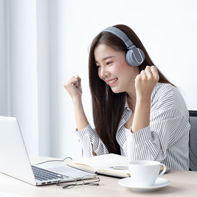 a woman sitting at a table in front of a laptop cheering