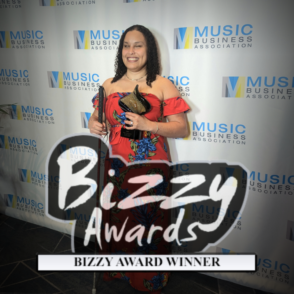 Precious Perez stands with an award behind the bizzy logo