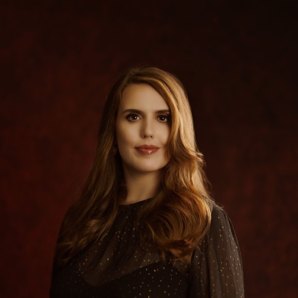 Photo of Pauline Maudy by Glenn Hunt. She wears a black and gold long-sleeved dress and looks straight into the camera.