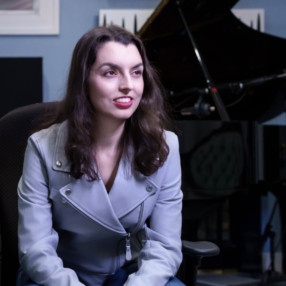 Shelby Lock, a brunette, in her recording studio Silver Moon Sound with a grand piano and microphones in the background.
